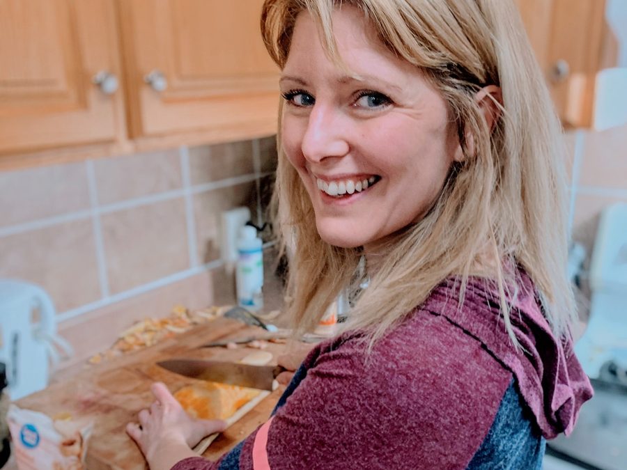 Kay cooking at home, turning from the cutting board