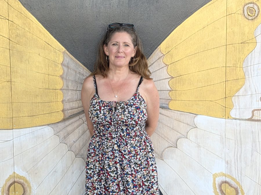 Kay in a floral dress in front of the butterfly wings mural in Charlottetown